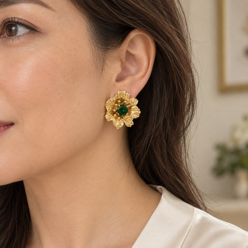 Model wearing a vintage gold-plated flower stud earring with a green rhinestone and cream blouse.