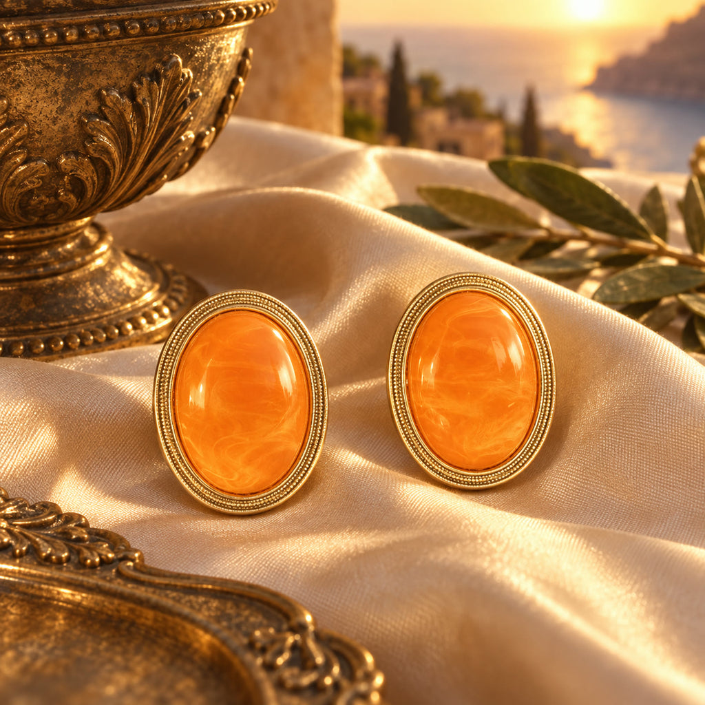 Orange amber gold-plated oval earrings styled on champagne silk