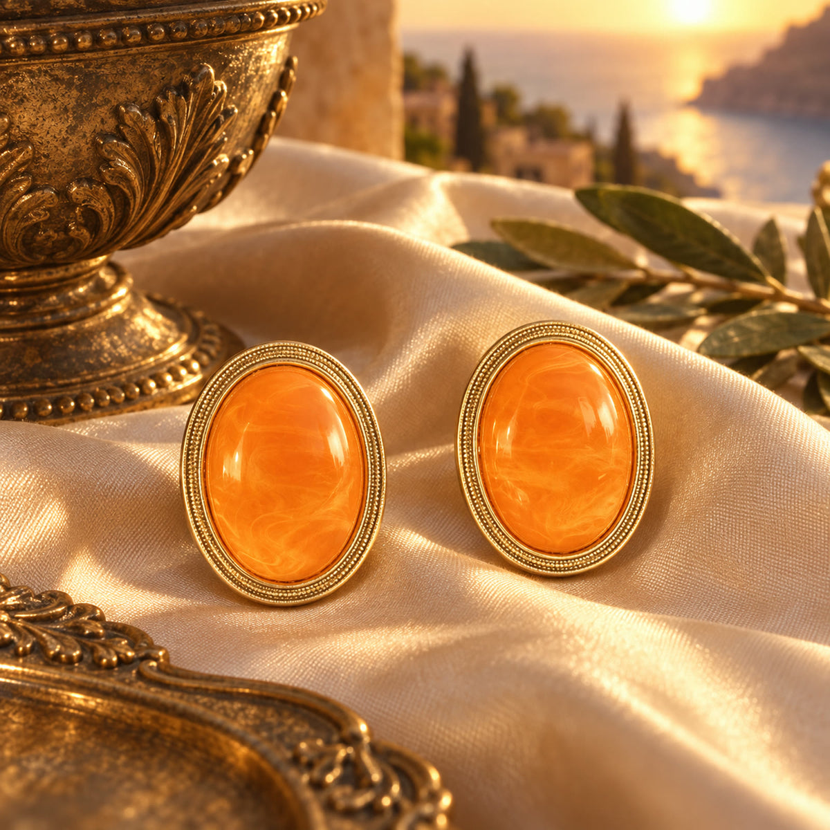Orange amber gold-plated oval earrings styled on champagne silk