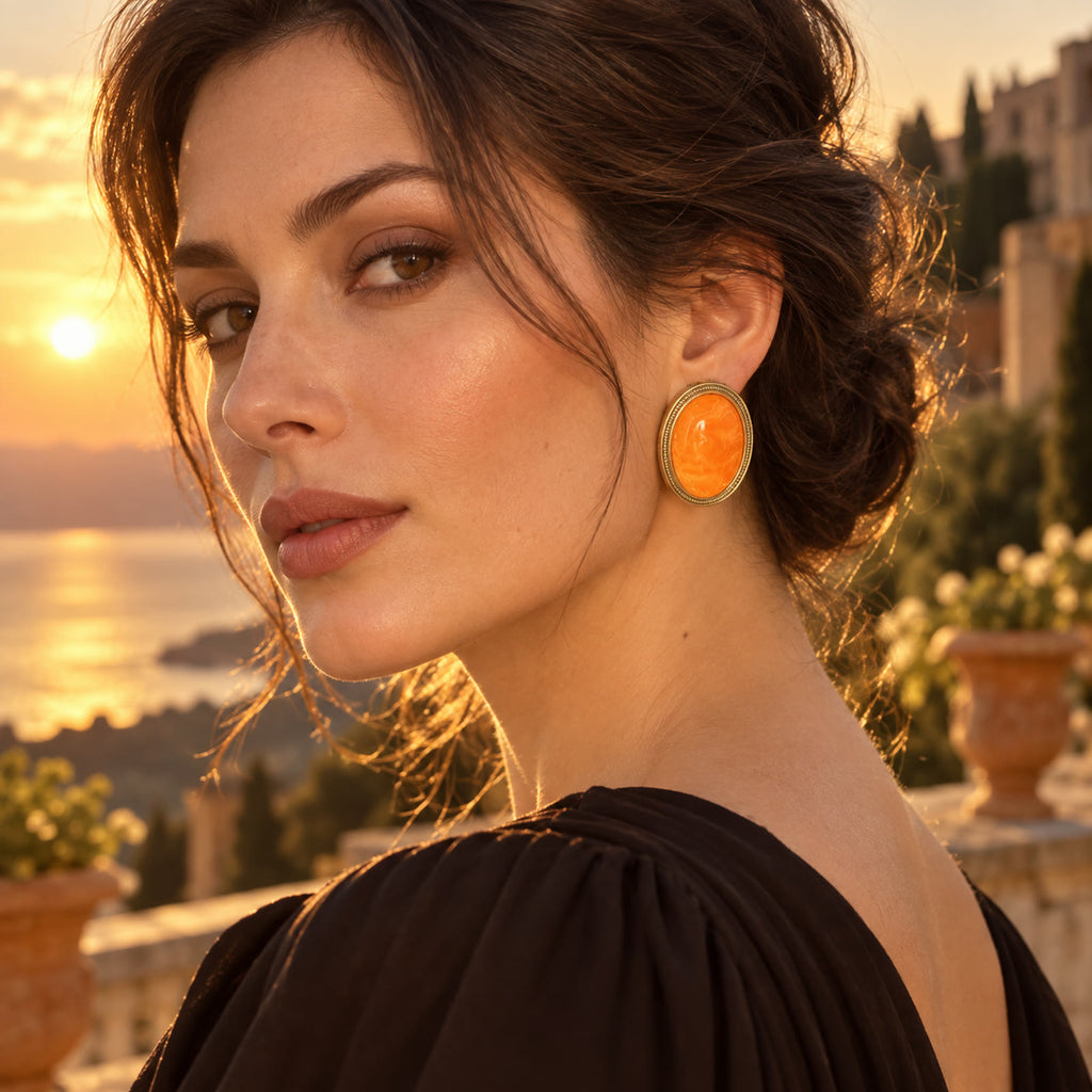 European woman wearing orange amber gold-plated earrings in a sunset evening setting