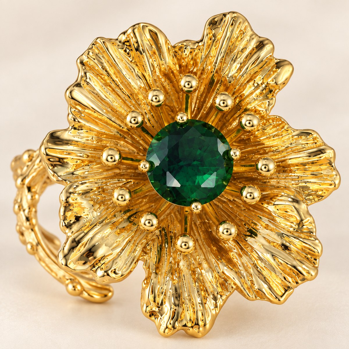 Close-up of the faceted green rhinestone and textured gold-plated flower petals