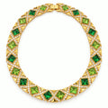 Vintage gold-plated necklace with alternating green rhinestones on a white background